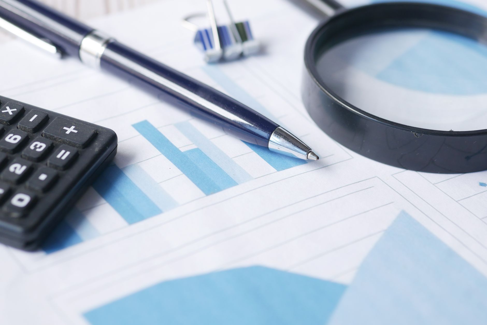 Financial analysis and commission statement audit on laptop with calculator and ledger