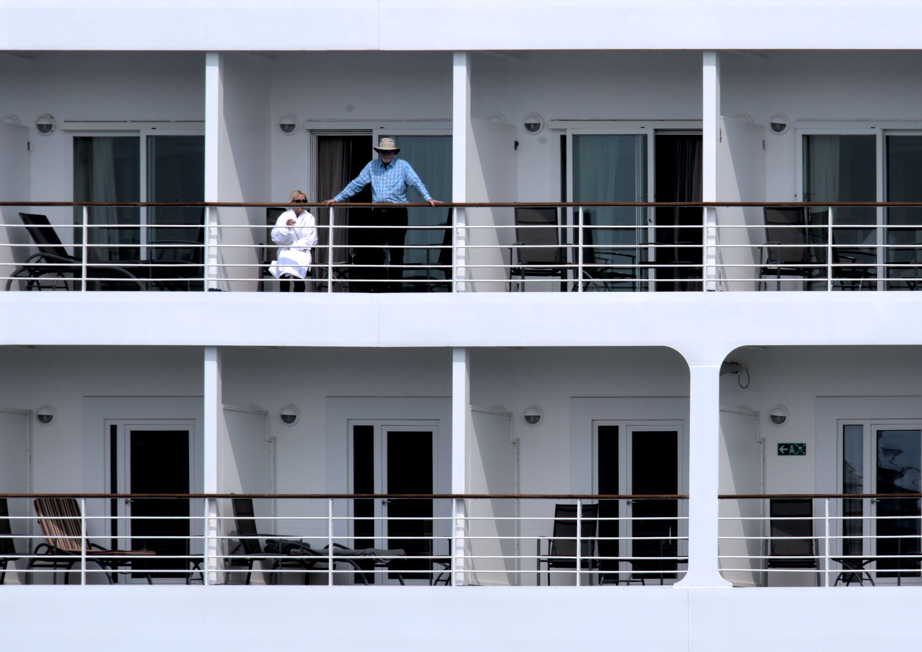 Luxury cruise ship balcony suite with sunny ocean view and lounge chairs