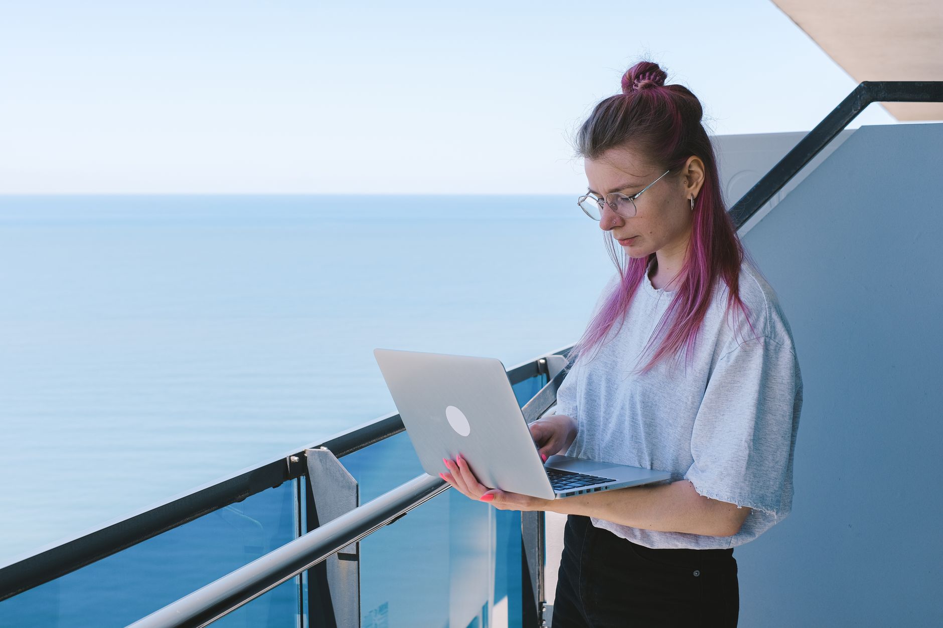 Luxury travel advisor curating custom itineraries on laptop on scenic hotel balcony